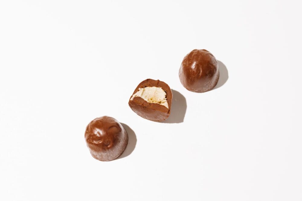 Three delta-9 peanut butter nuggets side by side diagonally, with the middle cut in half and on its side as if it's had a bite taken out of it